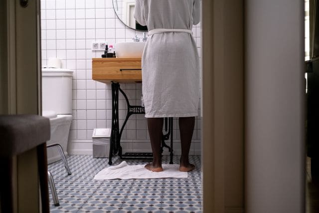 A bathroom safety setup for an older adult with a wall-mounted grab bar and a non-slip mat.