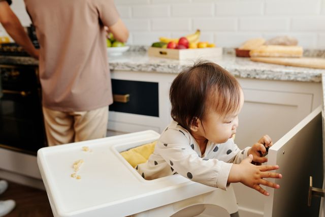 A high chair on a flat kitchen floor with a secure harness and tray, away from walls and counters.